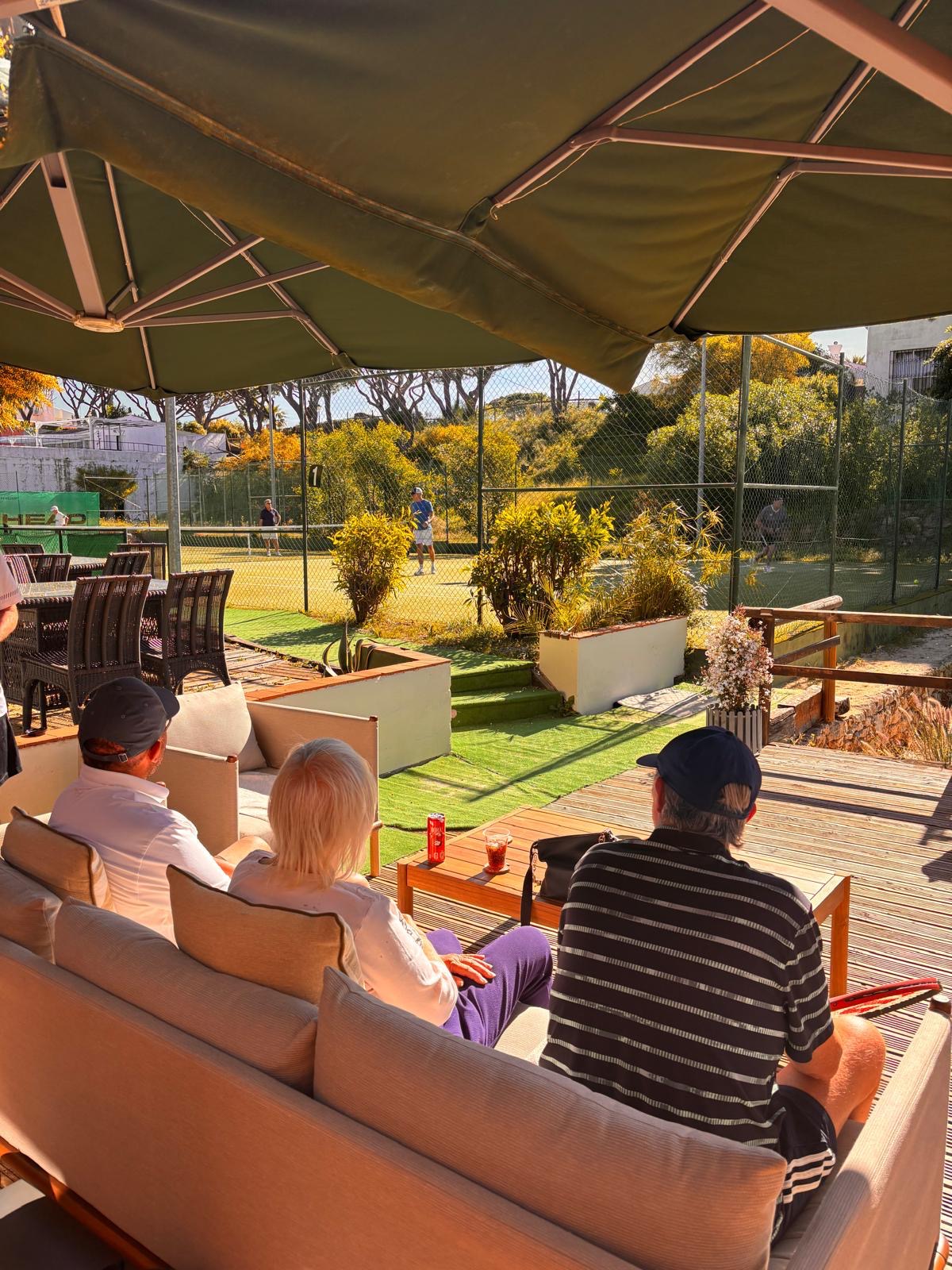 Guests relaxing at the Jardins clubhouse overlooking the tennis courts